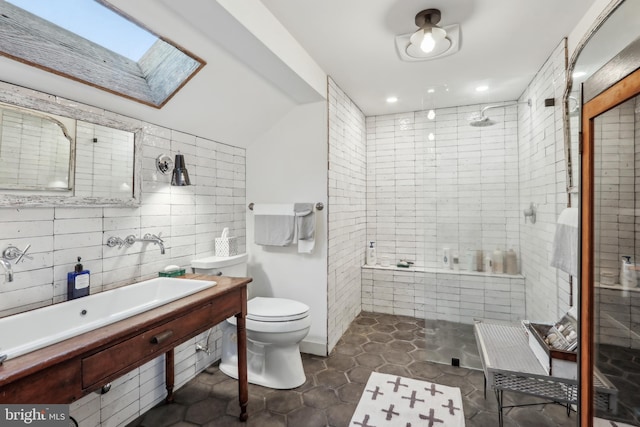 bathroom featuring a skylight, decorative backsplash, tiled shower, toilet, and tile walls