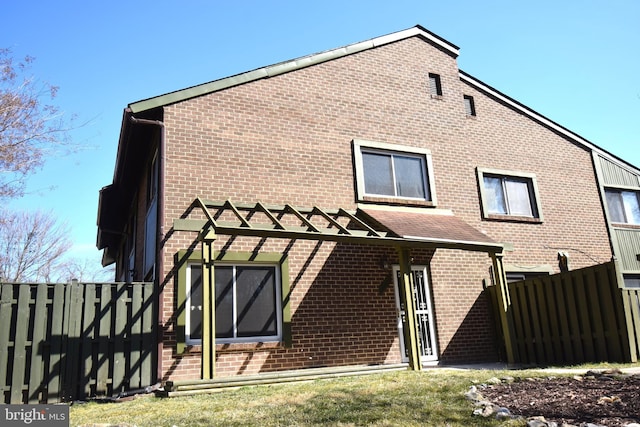 rear view of property with fence and brick siding