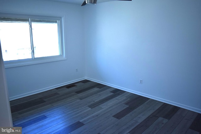 unfurnished room featuring dark wood-style flooring, visible vents, and baseboards