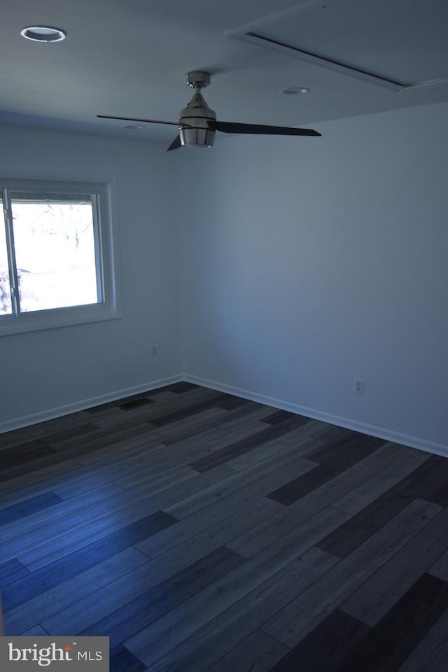 unfurnished room with dark wood-style flooring, ceiling fan, and baseboards