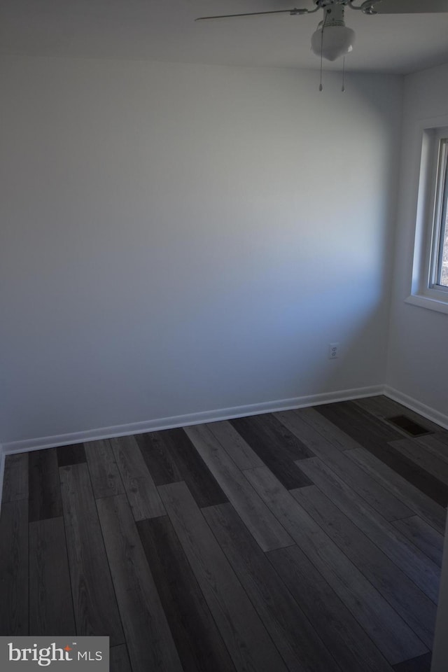 empty room with visible vents, dark wood finished floors, baseboards, and ceiling fan