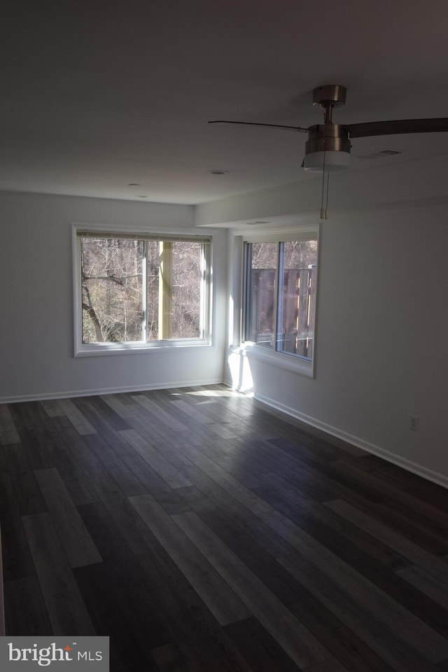 empty room with dark wood-style floors, baseboards, and a ceiling fan