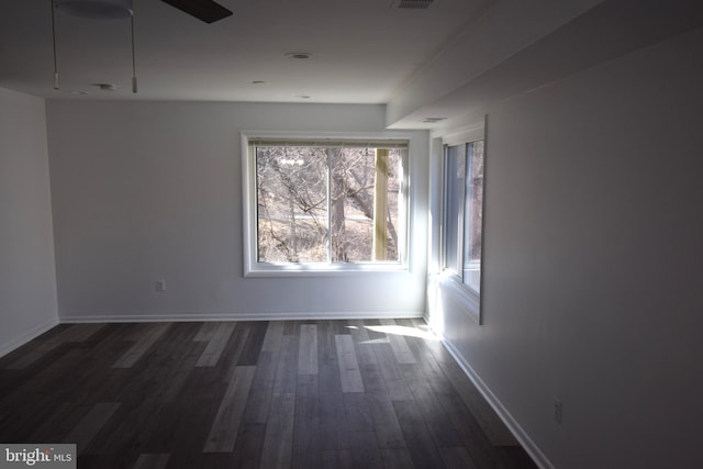 spare room with visible vents, dark wood-style flooring, a ceiling fan, and baseboards