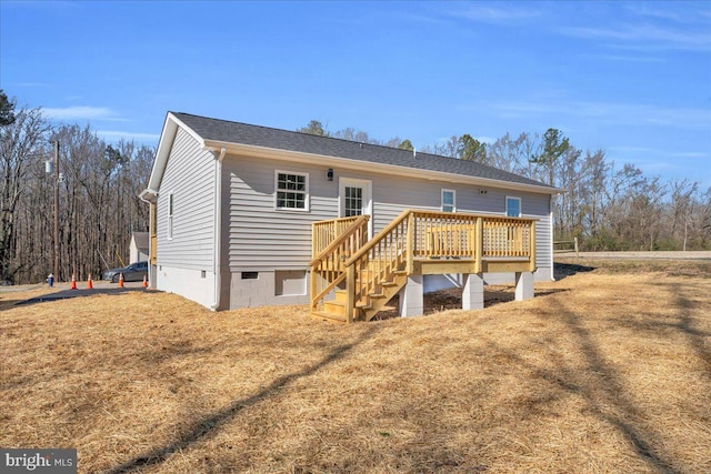 rear view of property featuring a shingled roof, crawl space, a lawn, and a wooden deck