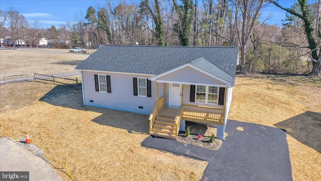 view of front facade with a porch, a shingled roof, fence, crawl space, and a front yard