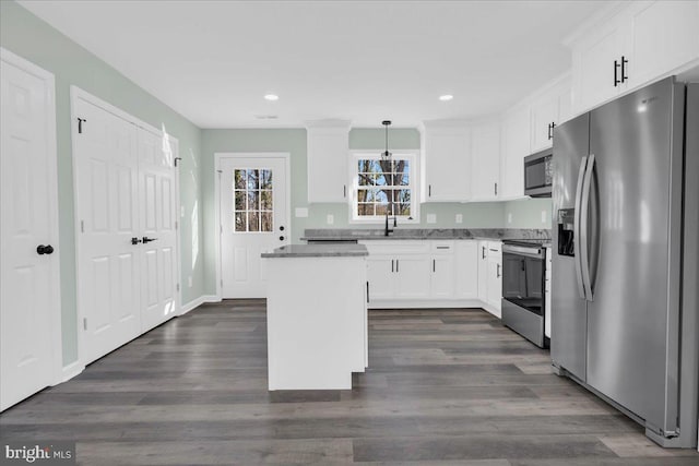 kitchen with white cabinets, a kitchen island, stainless steel appliances, and dark wood finished floors