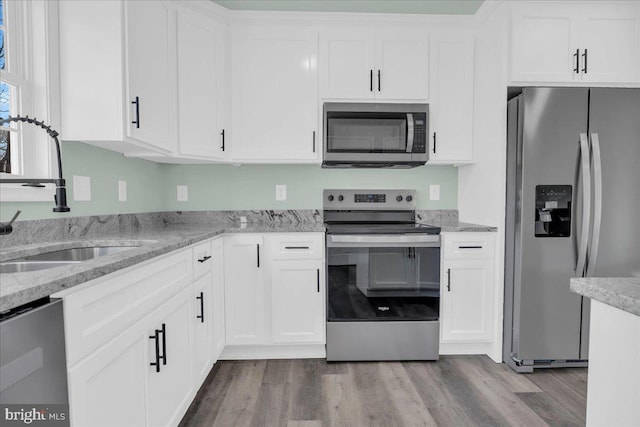 kitchen featuring stainless steel appliances, wood finished floors, and white cabinetry