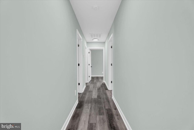 corridor featuring dark wood-style floors, visible vents, and baseboards