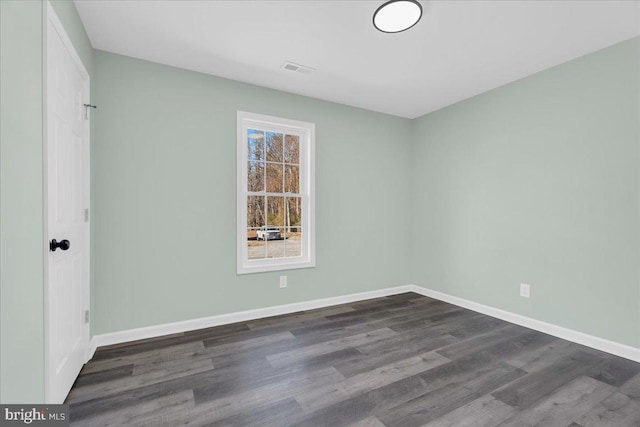 unfurnished room featuring dark wood-type flooring, visible vents, and baseboards