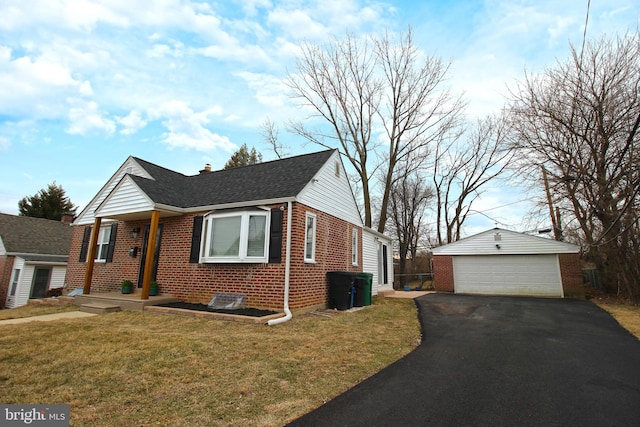 view of front of house featuring an outbuilding, a garage, brick siding, roof with shingles, and a front lawn