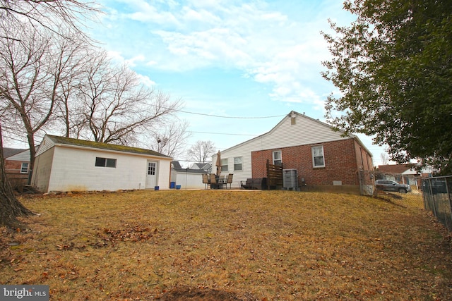 rear view of house featuring crawl space, brick siding, a lawn, and fence