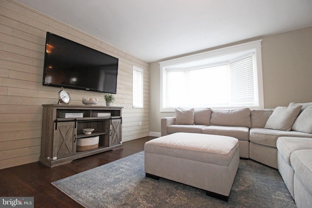 living area with dark wood-style floors and wooden walls