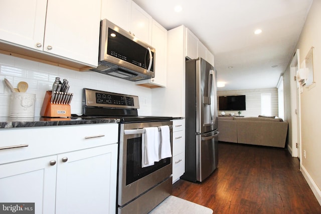 kitchen featuring dark countertops, appliances with stainless steel finishes, dark wood-type flooring, open floor plan, and white cabinetry