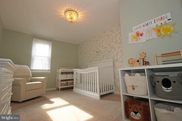 bedroom featuring a nursery area, baseboards, carpet, and wallpapered walls