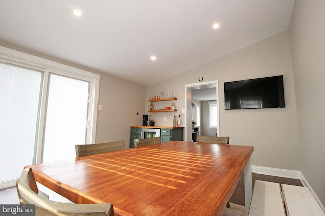 dining area with bar, baseboards, vaulted ceiling, and recessed lighting