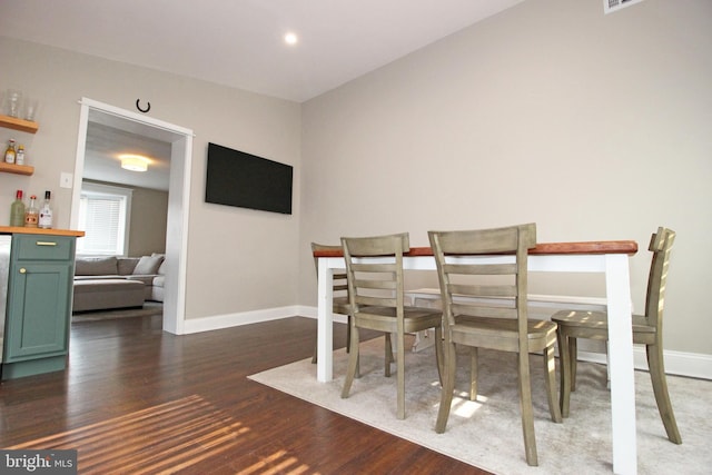 dining room featuring a bar, baseboards, wood finished floors, and recessed lighting