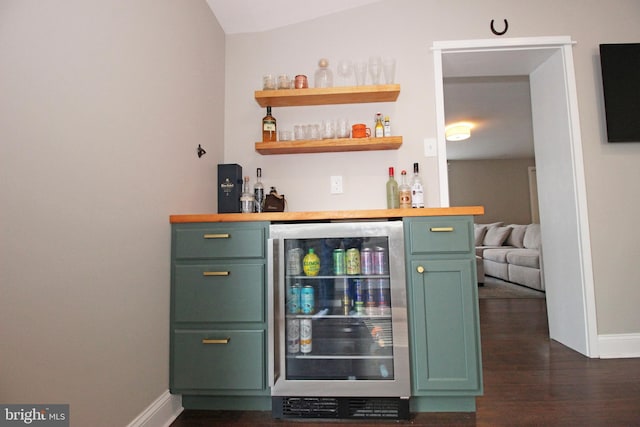 bar with lofted ceiling, beverage cooler, dark wood-type flooring, baseboards, and a bar