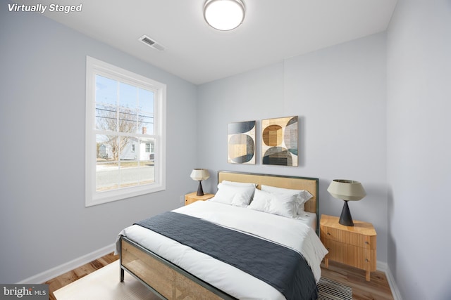 bedroom featuring baseboards, visible vents, and wood finished floors