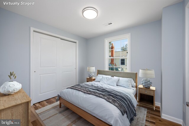 bedroom featuring baseboards, a closet, visible vents, and wood finished floors