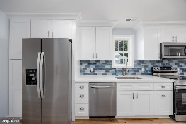 kitchen with a sink, white cabinetry, light countertops, appliances with stainless steel finishes, and tasteful backsplash