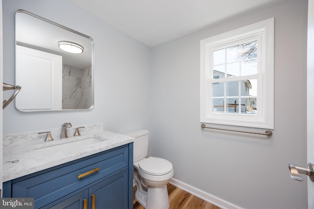 bathroom with wood finished floors, vanity, toilet, and baseboards