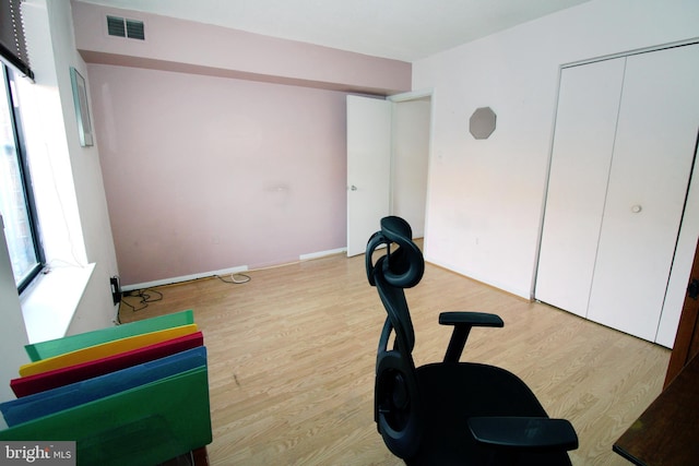 workout area with wood finished floors, visible vents, and baseboards