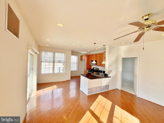 kitchen featuring light wood finished floors, visible vents, brown cabinetry, dark countertops, and stainless steel appliances