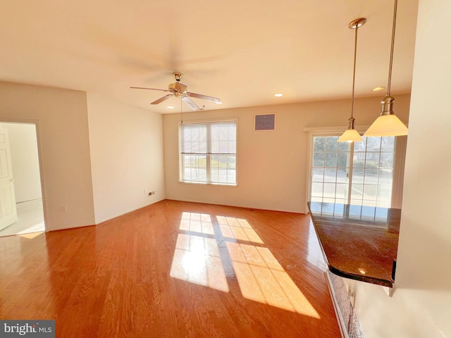 unfurnished room featuring a healthy amount of sunlight, visible vents, and wood finished floors