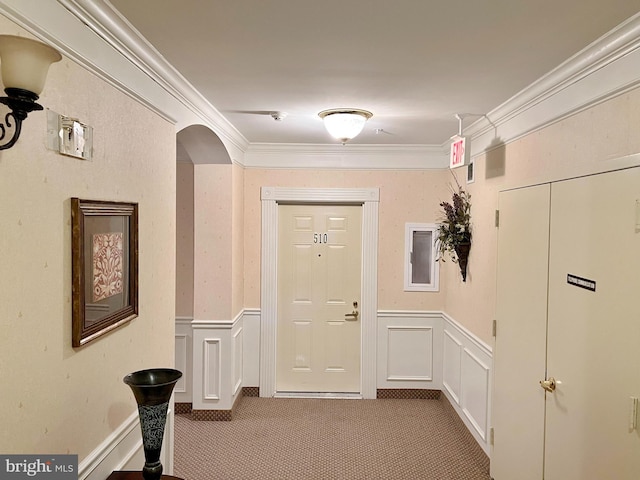 hallway featuring arched walkways, ornamental molding, wainscoting, and carpet flooring