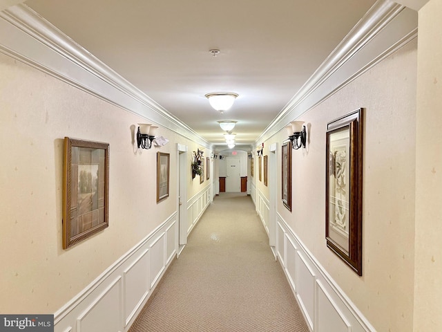 corridor with crown molding, light colored carpet, and a decorative wall