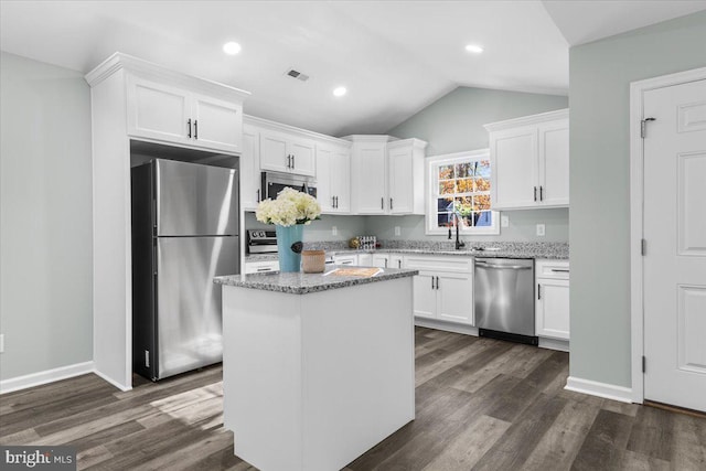 kitchen with dark wood-style floors, stainless steel appliances, light stone countertops, and white cabinets