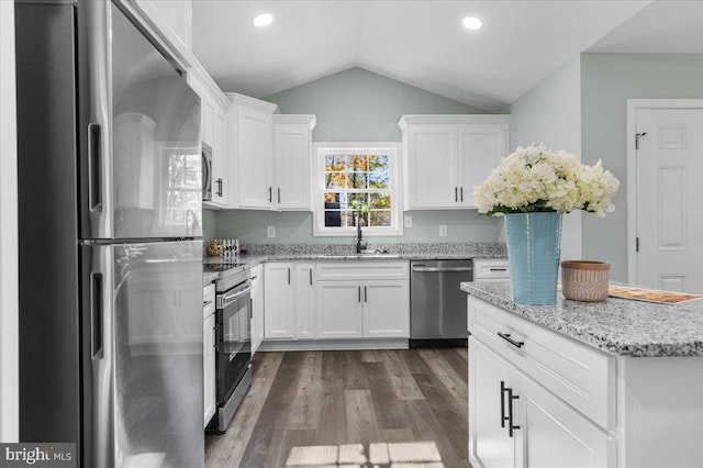 kitchen featuring stainless steel appliances, lofted ceiling, dark wood-type flooring, white cabinetry, and a sink