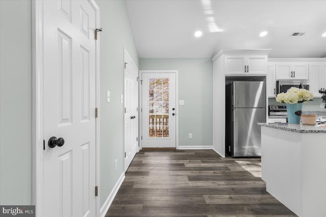 kitchen featuring visible vents, dark wood finished floors, white cabinets, appliances with stainless steel finishes, and light stone counters