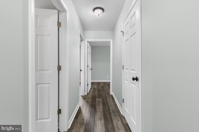 hallway featuring dark wood-style floors and baseboards