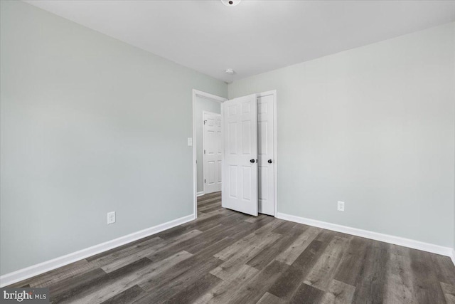 unfurnished bedroom featuring a closet, baseboards, and wood finished floors