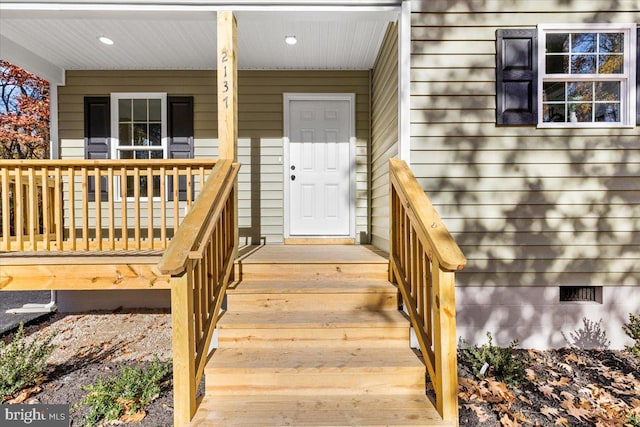 view of exterior entry featuring crawl space and covered porch