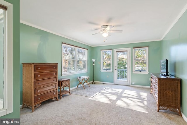 sitting room with a healthy amount of sunlight, crown molding, and baseboards