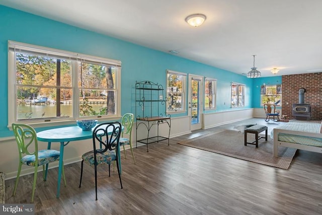 dining space featuring a wood stove, baseboards, and wood finished floors