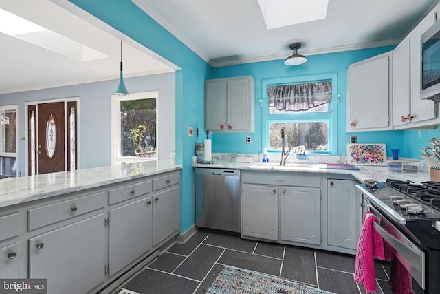 kitchen with stainless steel appliances, a skylight, a sink, ornamental molding, and decorative light fixtures