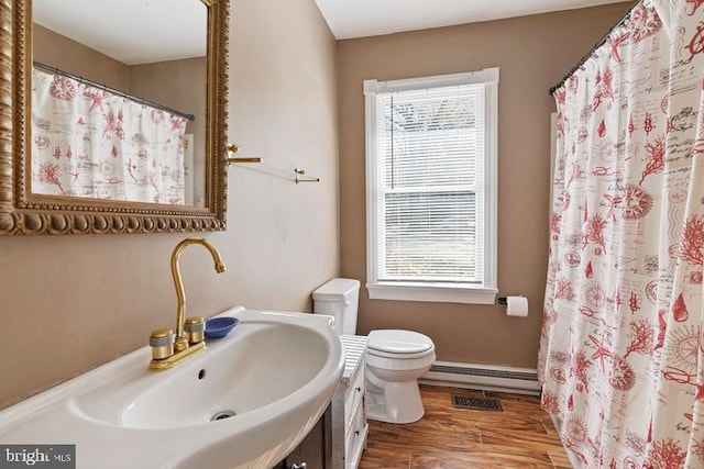 full bath with toilet, a shower with shower curtain, wood finished floors, vanity, and baseboard heating