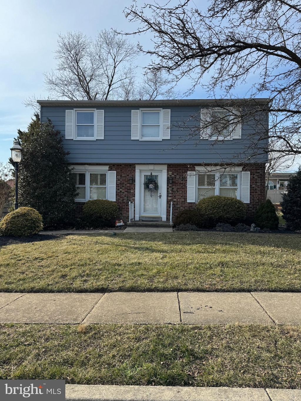 colonial inspired home with brick siding and a front lawn