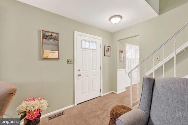 carpeted entrance foyer featuring stairs, baseboards, and visible vents