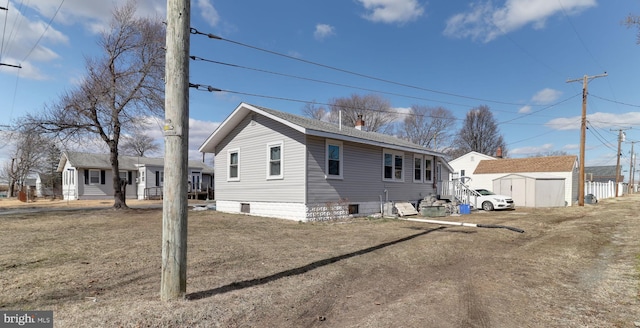 back of property featuring roof with shingles, an outdoor structure, a chimney, and a storage unit