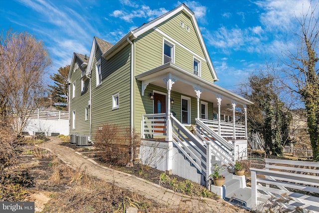 view of front facade featuring a porch, cooling unit, fence, and stairs