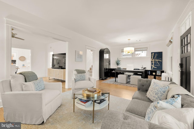 living area featuring stairway, arched walkways, and wood finished floors