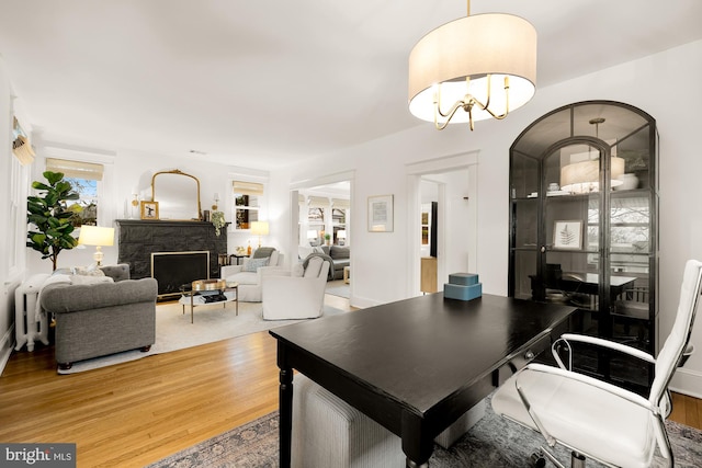 dining room featuring light wood-type flooring, a fireplace, and an inviting chandelier