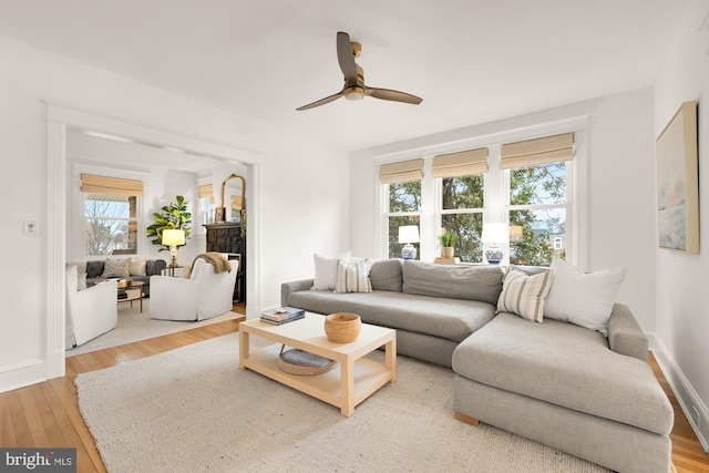 living room featuring ceiling fan, wood finished floors, and baseboards