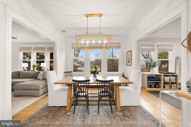 dining area featuring an inviting chandelier, plenty of natural light, visible vents, and wood finished floors