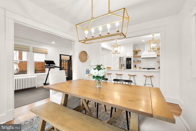 dining room featuring baseboards, light wood finished floors, and radiator heating unit