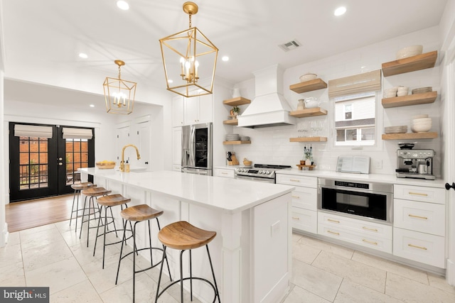 kitchen featuring visible vents, decorative backsplash, appliances with stainless steel finishes, premium range hood, and open shelves